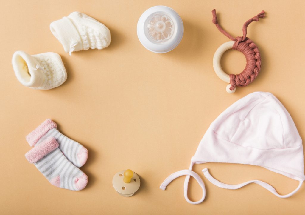 baby-s-sock-pair-woolen-shoes-pacifier-cap-milk-bottle-toy-orange-background